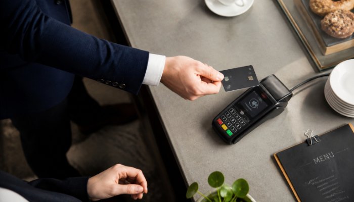 High-quality overhead shot of a person using a credit card for a contactless payment at a modern cafe, soft morning ligh