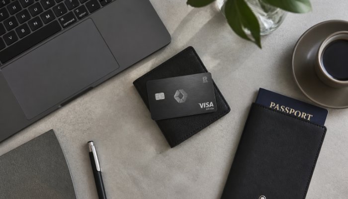 An overhead shot of a clean, minimalist workstation with a sleek dark laptop, a high-end metal credit card on a leather
